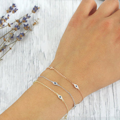 Hand wearing multiple bracelets on a light wooden surface with lavender flowers.