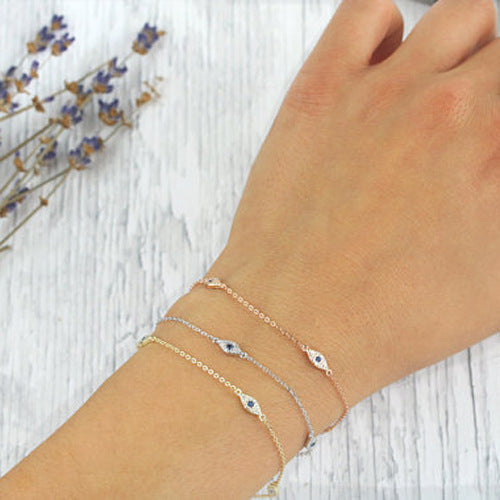 Hand wearing multiple bracelets on a light wooden surface with lavender flowers.